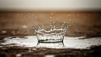 The long awaited rain storm. One rain drop in macro against the arid scorched earth. water crown.